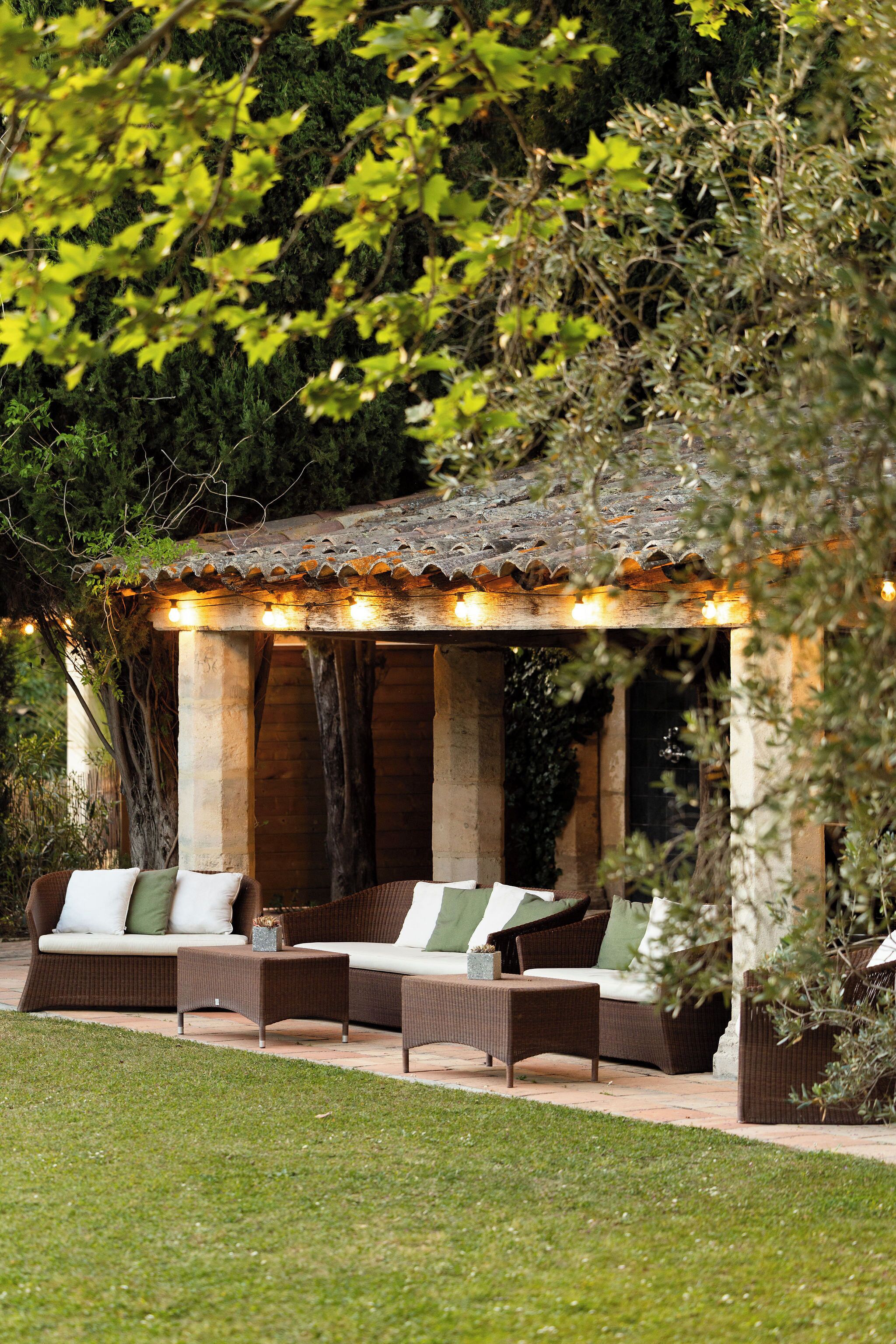 A covered outdoor seating area with wicker furniture and a tiled roof.