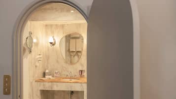 A bathroom with a marble vanity, a round mirror, a towel rack, and a wall-mounted phone.