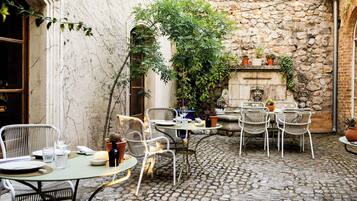 An outdoor patio with stone walls, wicker furniture, and potted plants.