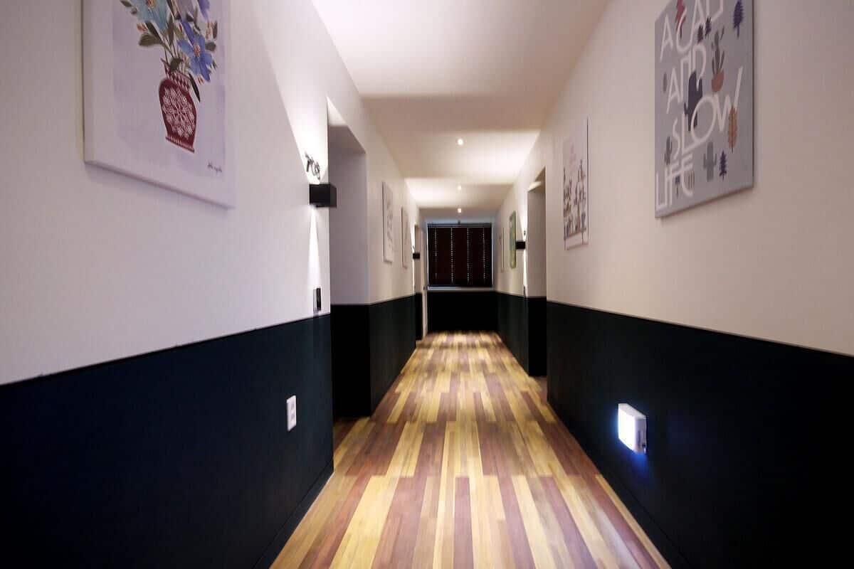 Un couloir doté d’un plancher en bois, de murs blancs et de moulures noires.