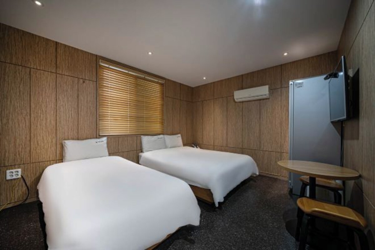 Une chambre d’hôtel avec deux lits, une petite table et un téléviseur.