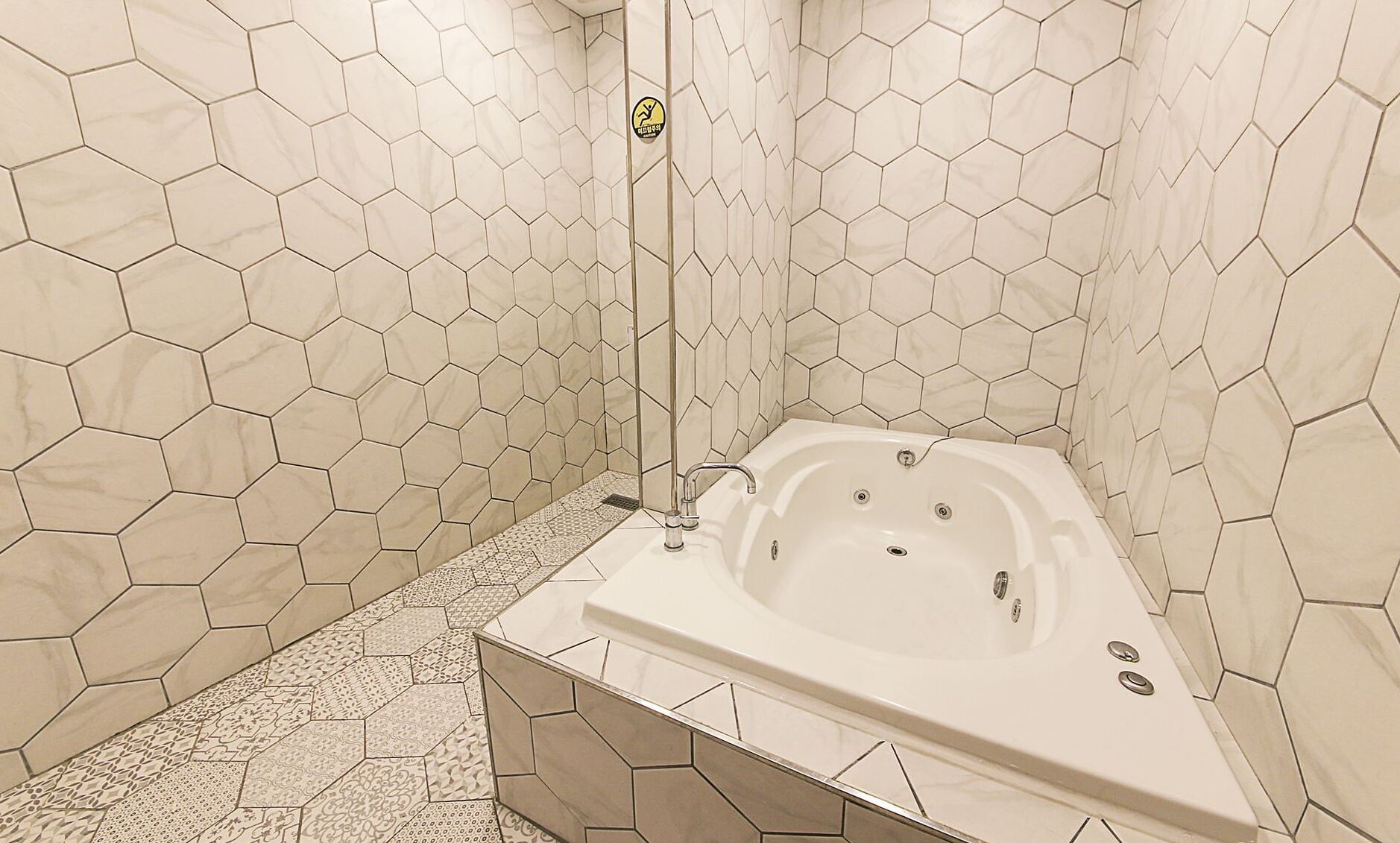 Un baño moderno con azulejos hexagonales, una bañera independiente y una zona de ducha.