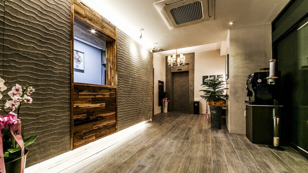 A modern hotel lobby with a wooden reception desk, a wall-mounted screen, and a coffee machine. - Ignis Hotel Busan Sports Complex Branch (Busan)