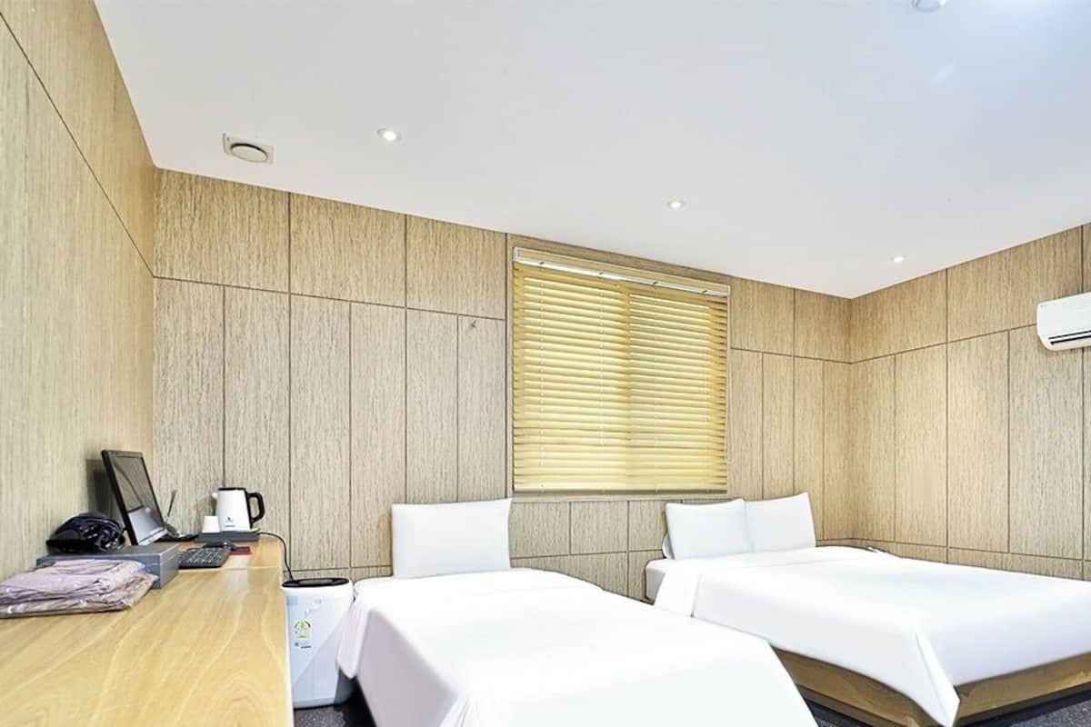 Une chambre d’hôtel moderne équipée de deux lits, d’un bureau, d’une machine à café et de la climatisation.