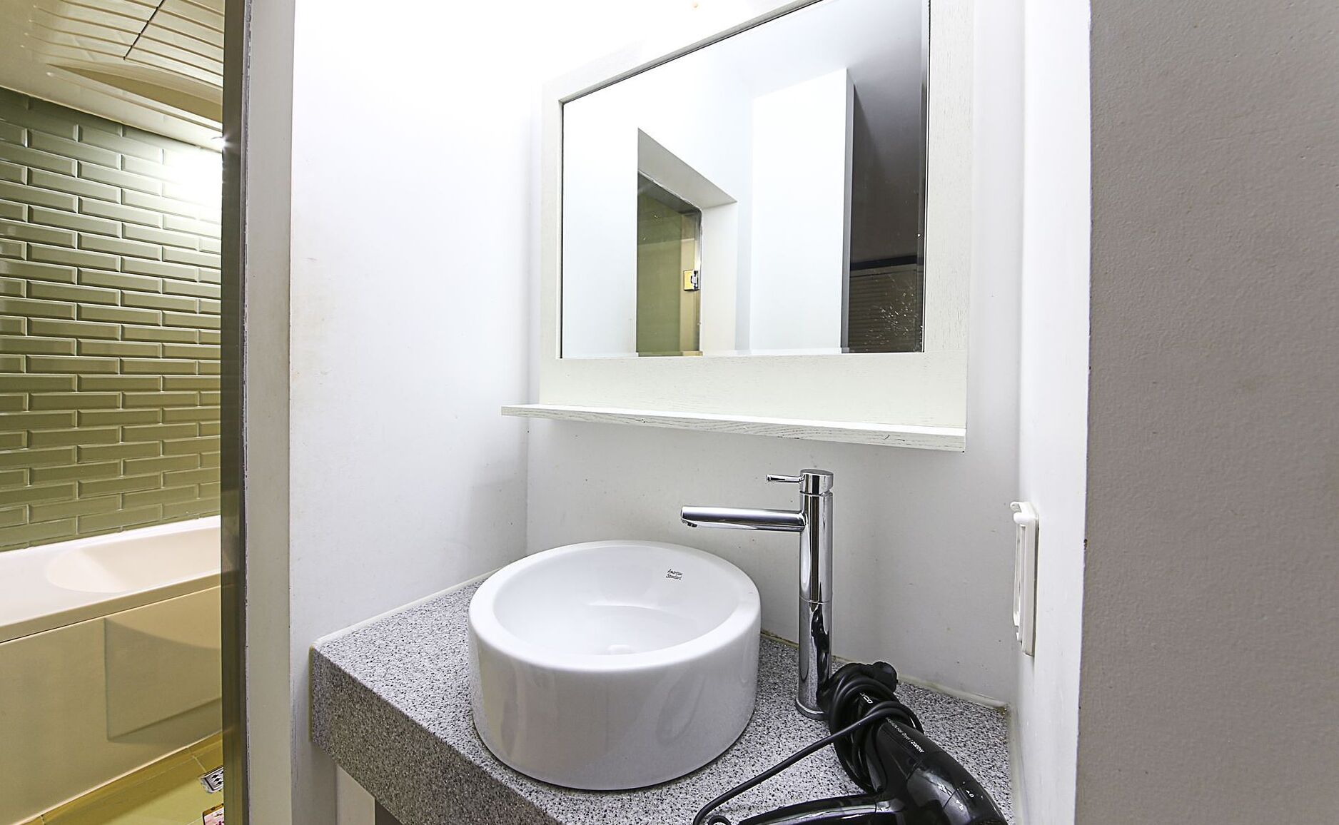 Un bagno con un lavandino bianco, uno specchio e un portasciugamani.