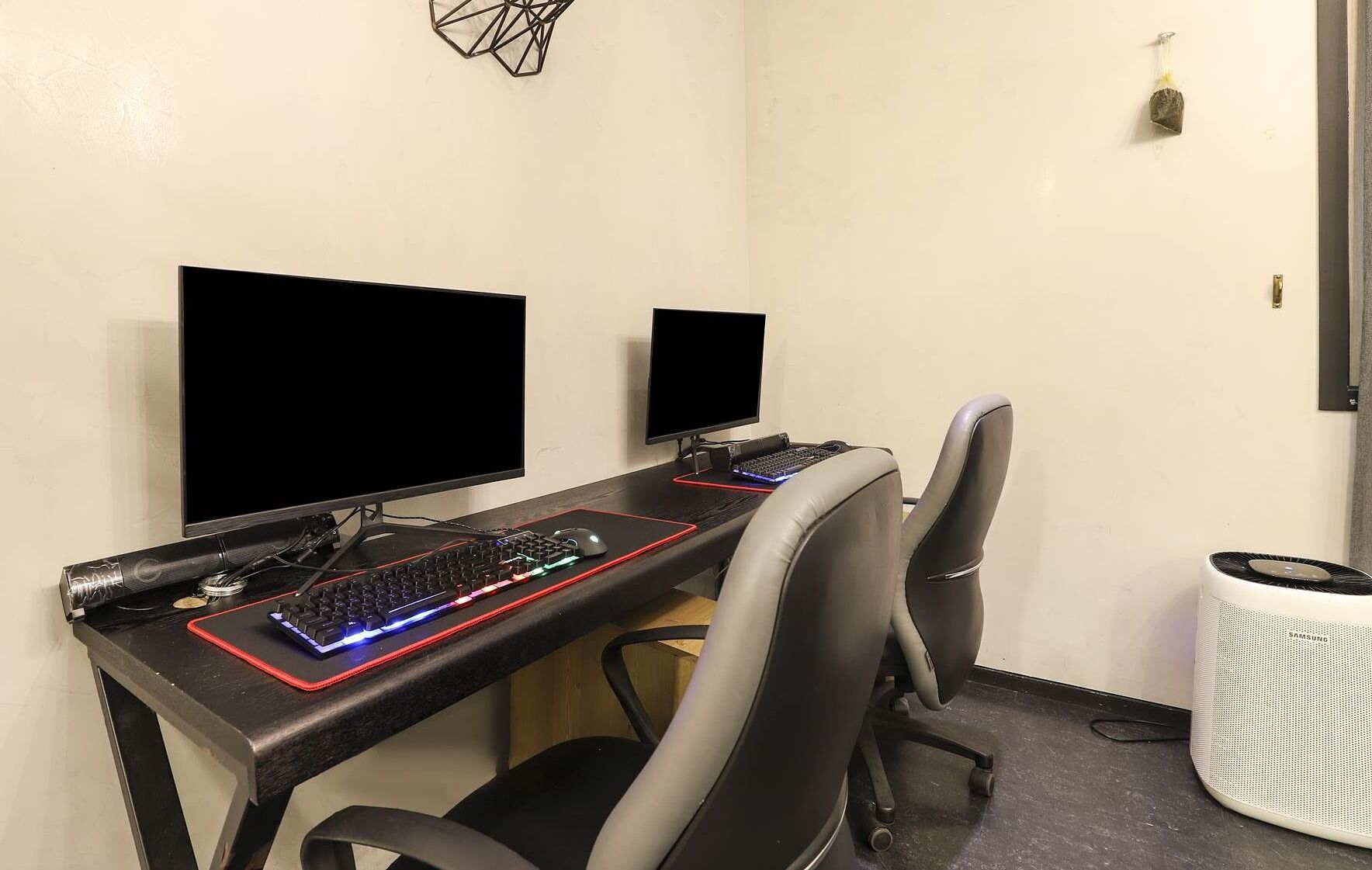 A computer desk with two monitors, a keyboard, and a mouse. There is a chair in front of the desk.