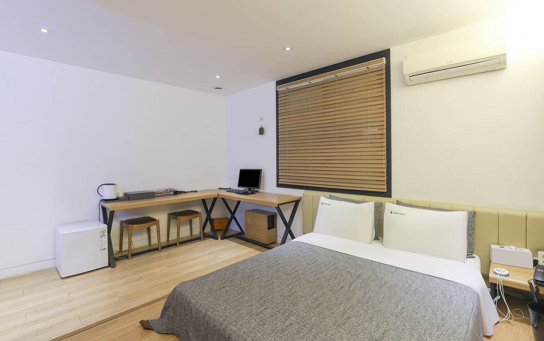A modern hotel room with a bed, desk, and computer.
