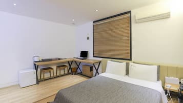 A modern hotel room with a bed, desk, and computer.