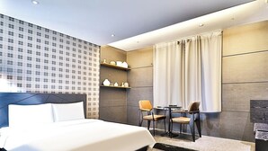 A modern hotel room with a large bed, two chairs, a small table, and a decorative shelf. - Ignis Hotel Busan Sports Complex Branch (Busan)