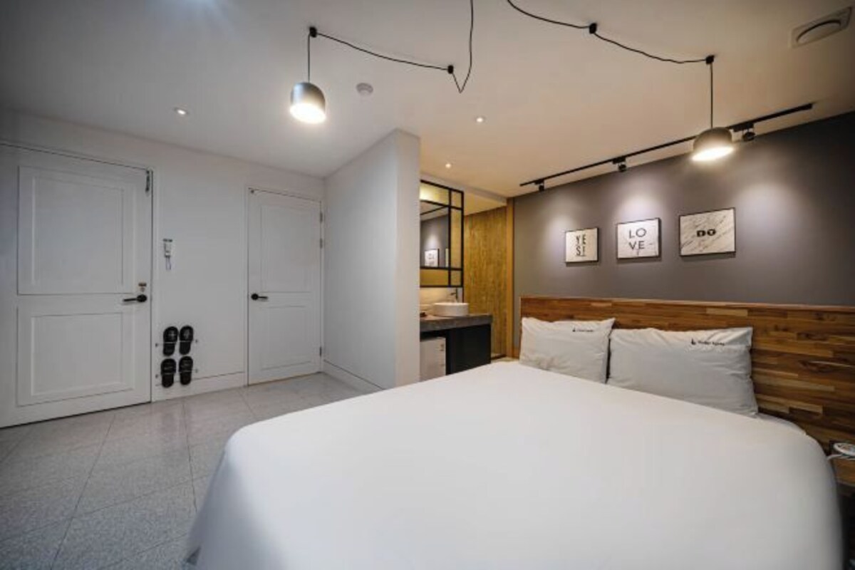 Une chambre à coucher moderne avec un grand lit, une tête de lit en bois et un miroir fixé au mur.