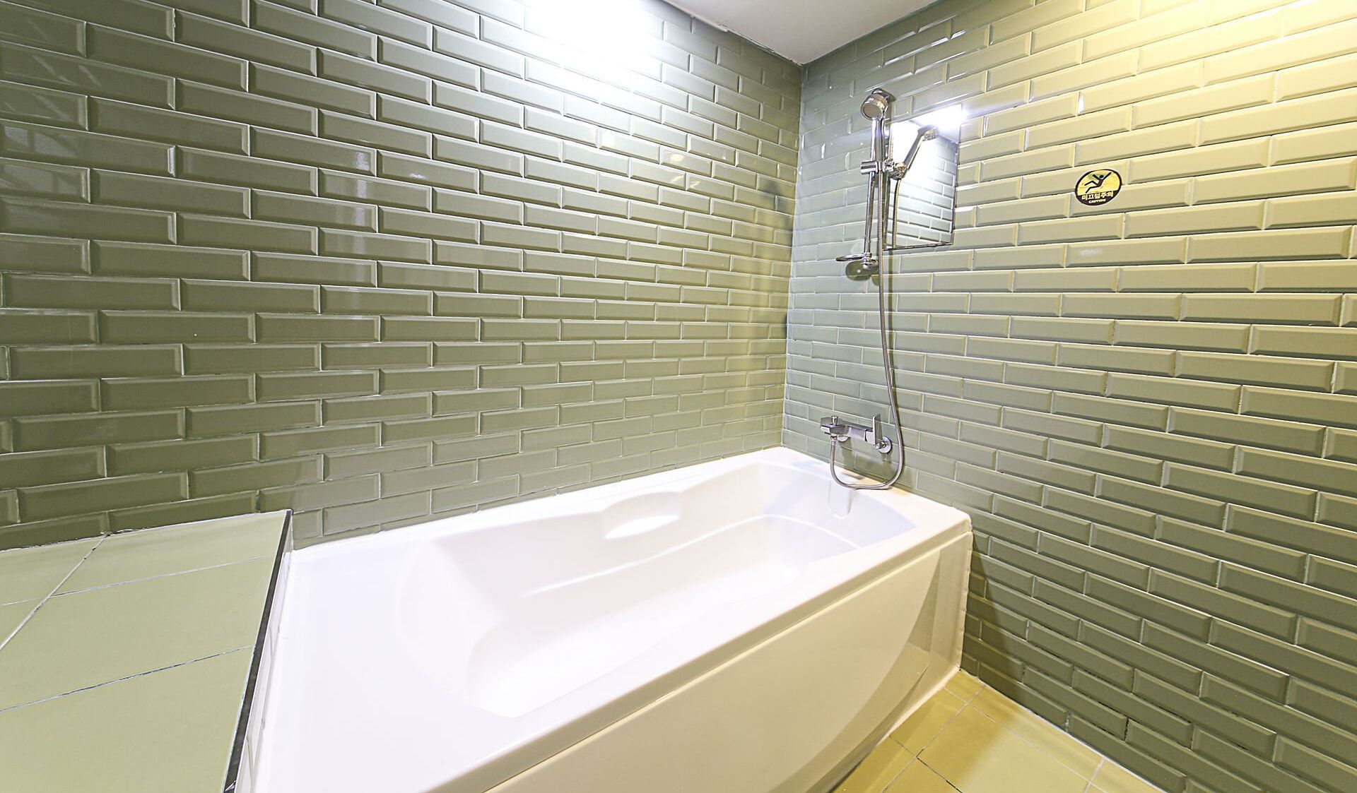 Un baño con una bañera blanca, paredes con azulejos verdes y una zona de ducha.