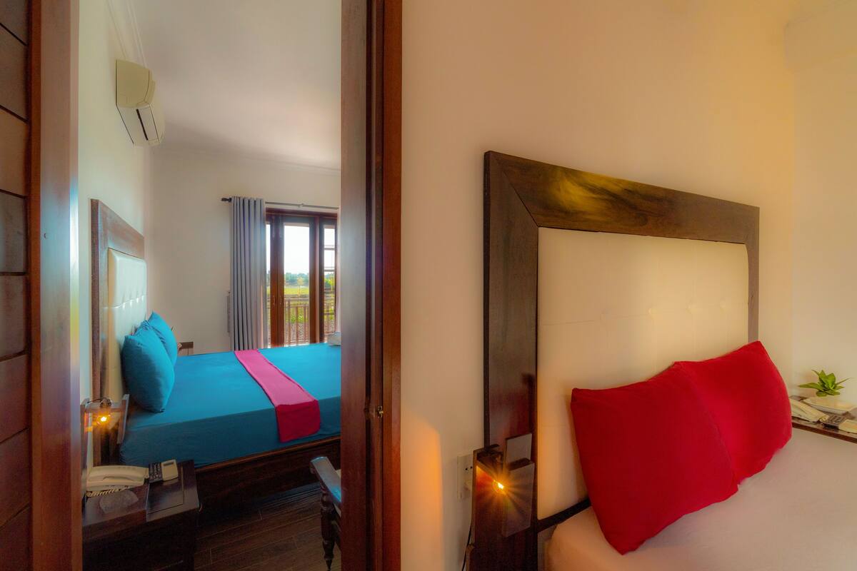 A hotel room with a bed, a nightstand, a telephone, and a window with curtains.