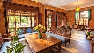 A spacious room with a wooden dining table, benches, and a brick wall.