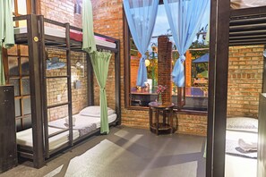A room with a bunk bed, a small table with a vase, and a window with curtains. - Flower’s House Hoi An (Da Nang)
