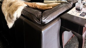 Una sala de estar moderna con un sofá de cuero, una mesa de centro de madera y un televisor de pantalla plana montado en la pared.