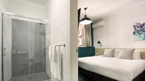 A modern hotel room with a glass-enclosed shower, a bed with white bedding, and a teal accent wall. - Greenacre Hotel (Greenacre)
