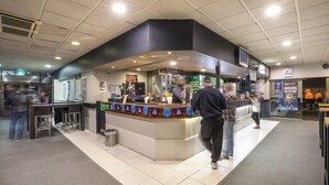 A counter area with a digital kiosk, seating, and a trash bin. - Greenacre Hotel (Greenacre)