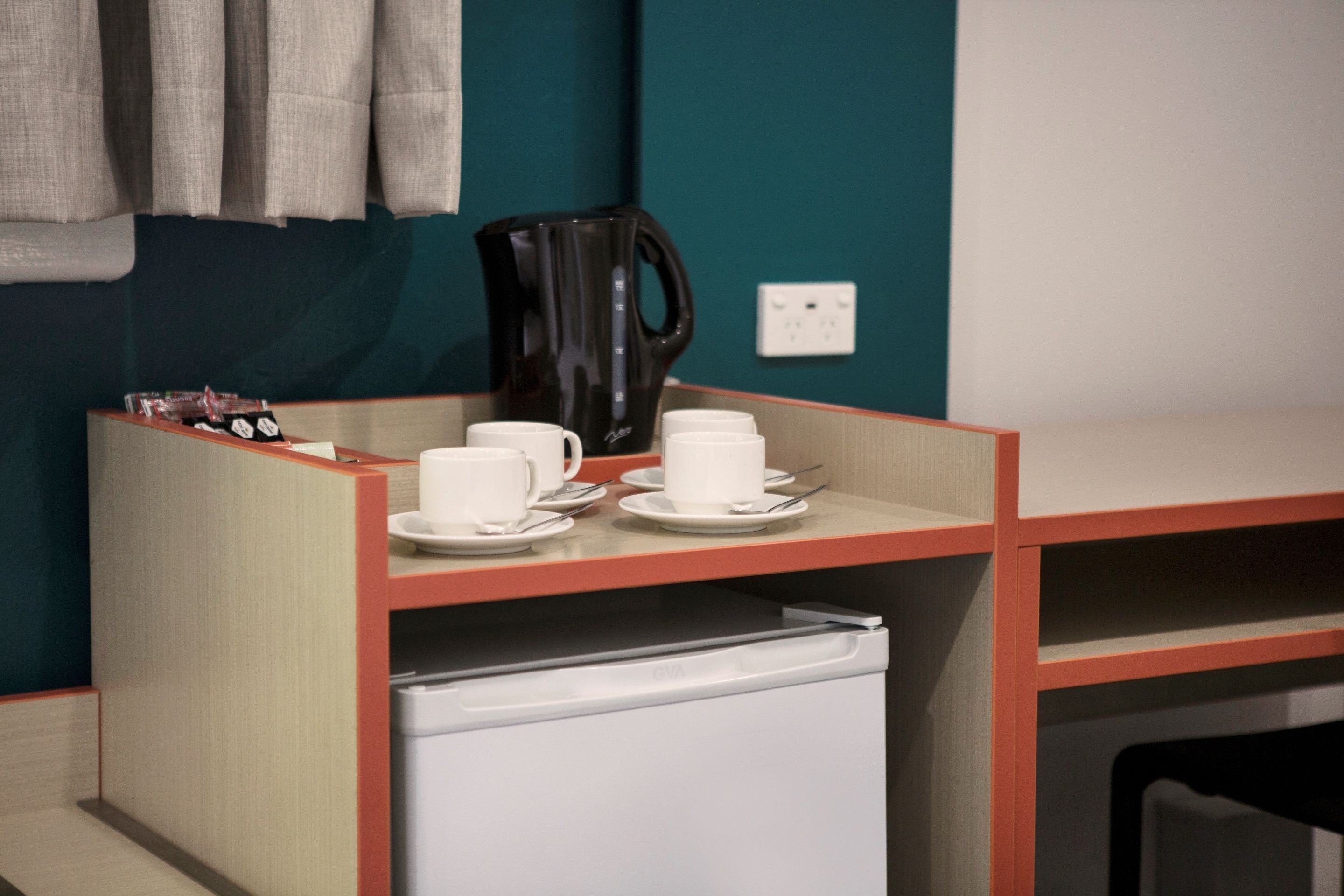 A kitchenette area with a coffee maker, cups, and a small refrigerator.
