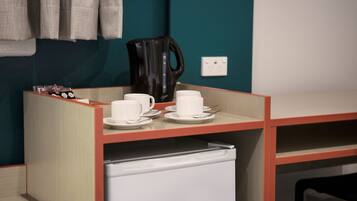 A kitchenette area with a coffee maker, cups, and a small refrigerator.