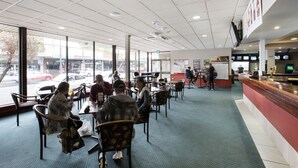 A spacious restaurant with large windows, a counter, and several tables and chairs. - Villawood Hotel (Villawood)
