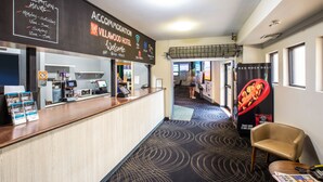 A reception area with a reception desk, a digital kiosk, and a poster advertising Red Rock Deli. - Villawood Hotel (Villawood)