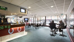 A spacious indoor seating area with a counter and a large screen displaying a game. - Villawood Hotel (Villawood)