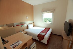 Habitación de hotel con cama, escritorio, televisión, ventana con vistas y mesita de noche.