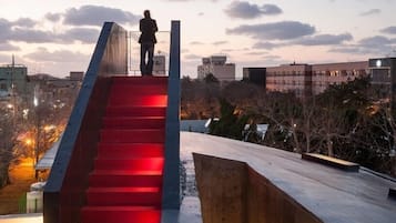 A staircase with red lighting leading to a platform, surrounded by buildings and trees.