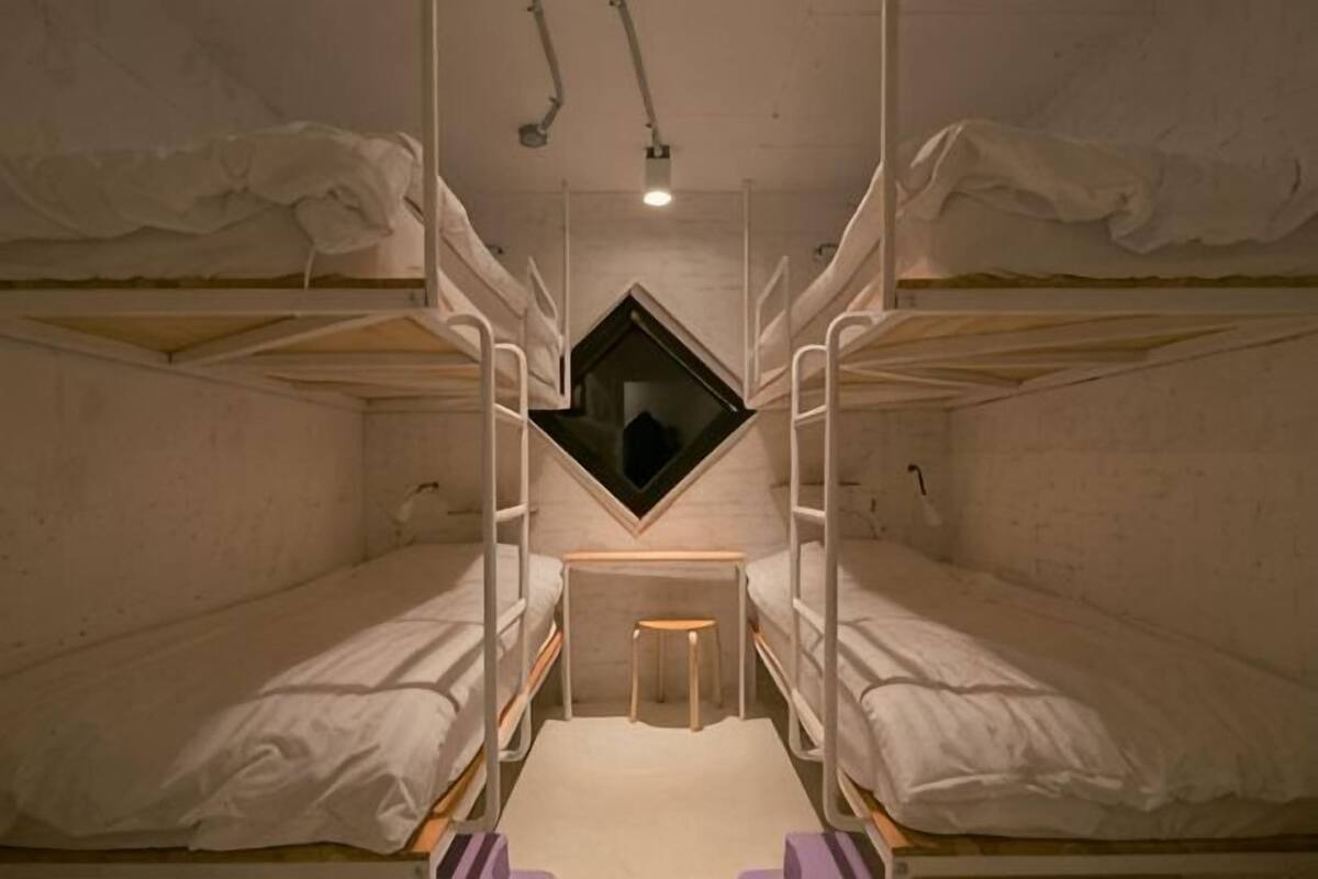 Une chambre de dortoir avec des lits superposés, une petite fenêtre et un bureau.