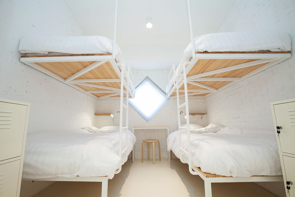 Une chambre avec des lits superposés, un bureau et un petit tabouret.