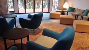 Ein stilvoller Lounge-Bereich mit blauen Sesseln, einem beigen Sofa und einem kleinen Tisch.