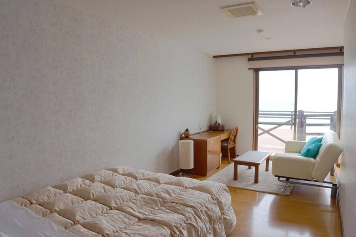 Een slaapkamer met een groot bed, een bureau, een stoel en een bank.