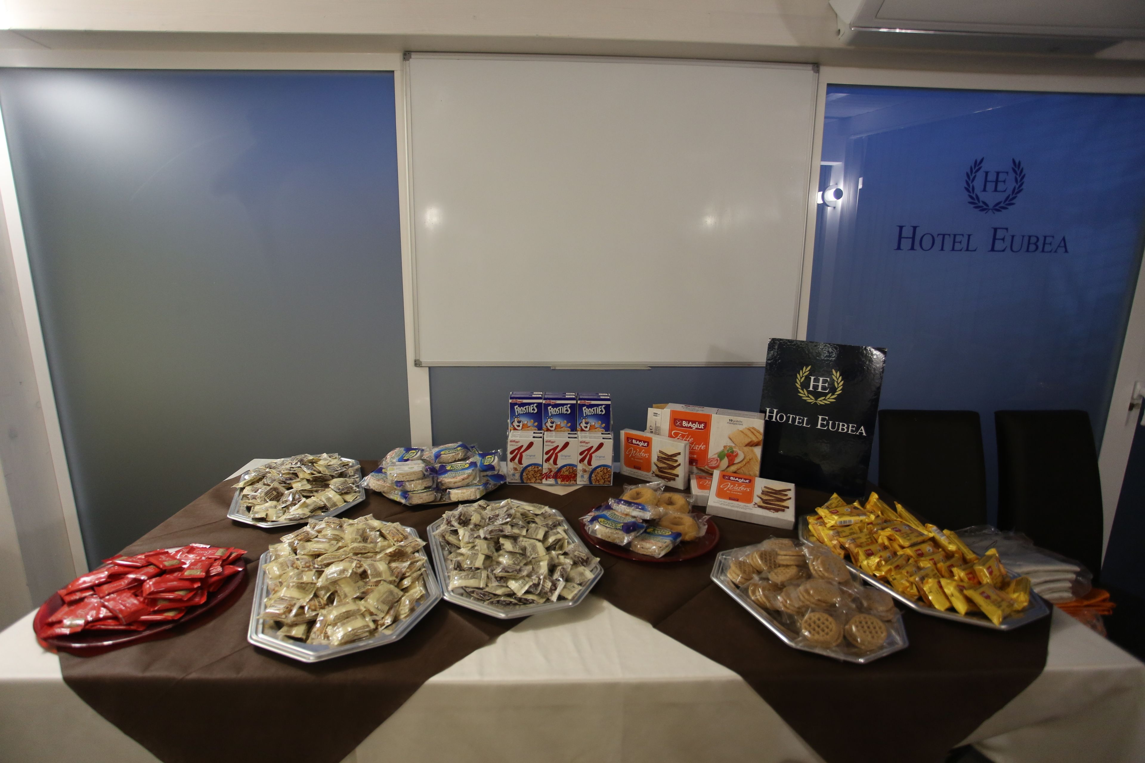A buffet table with various food items including pastries, bread, and snacks.