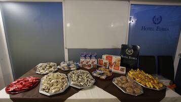 A buffet table with various food items including pastries, bread, and snacks.