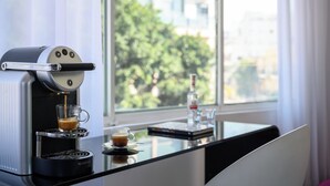 Een Nespresso koffiemachine op een tafel met een koffieglas, een boek en een waterfles.