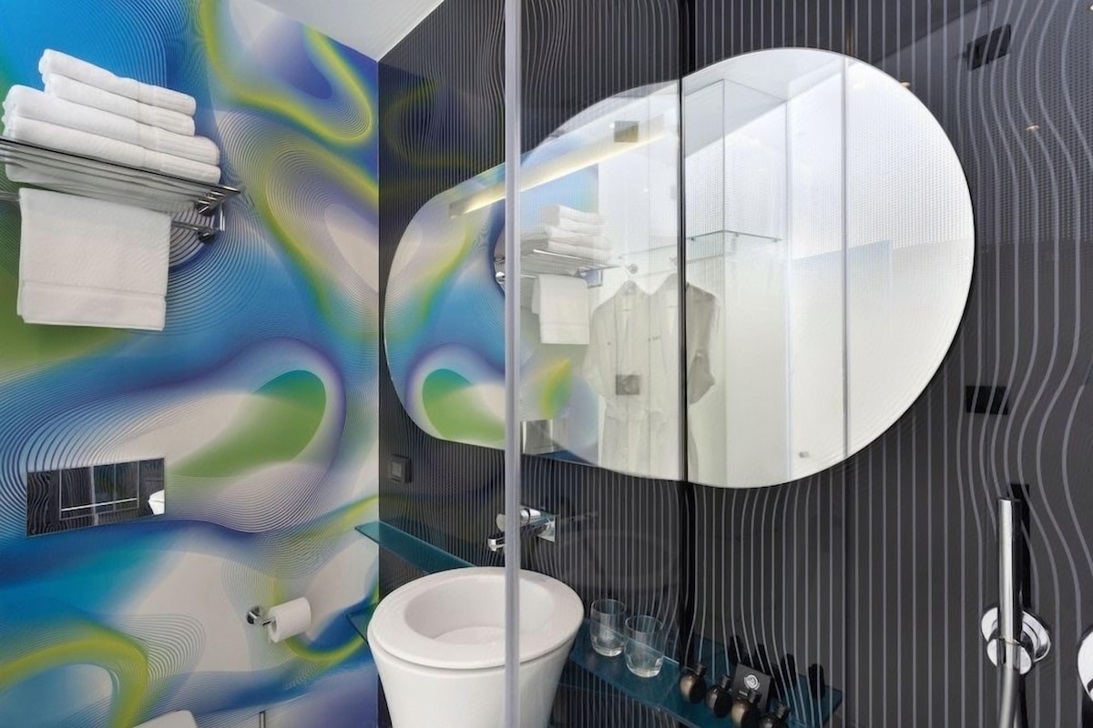 Ein modernes Badezimmer mit einem großen Spiegel, einem weißen Waschbecken und einer Duschkabine aus Glas.