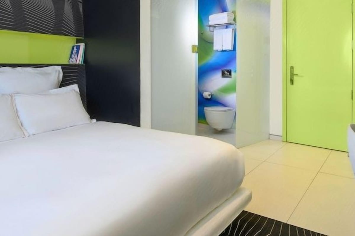 Ein Hotelzimmer mit einem Bett, einem Badezimmer und einer grünen Tür.