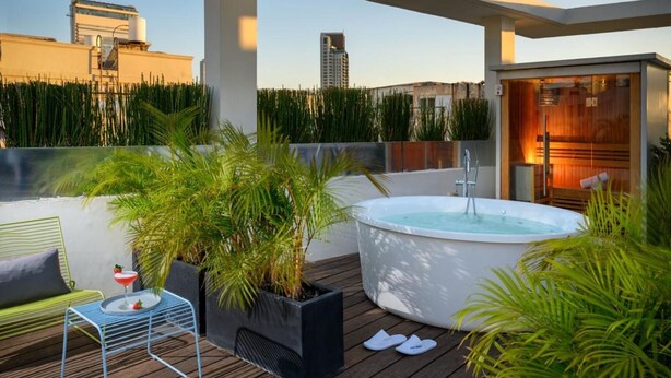 Een terras op het dak met een jacuzzi, zitgedeelte en potplanten.