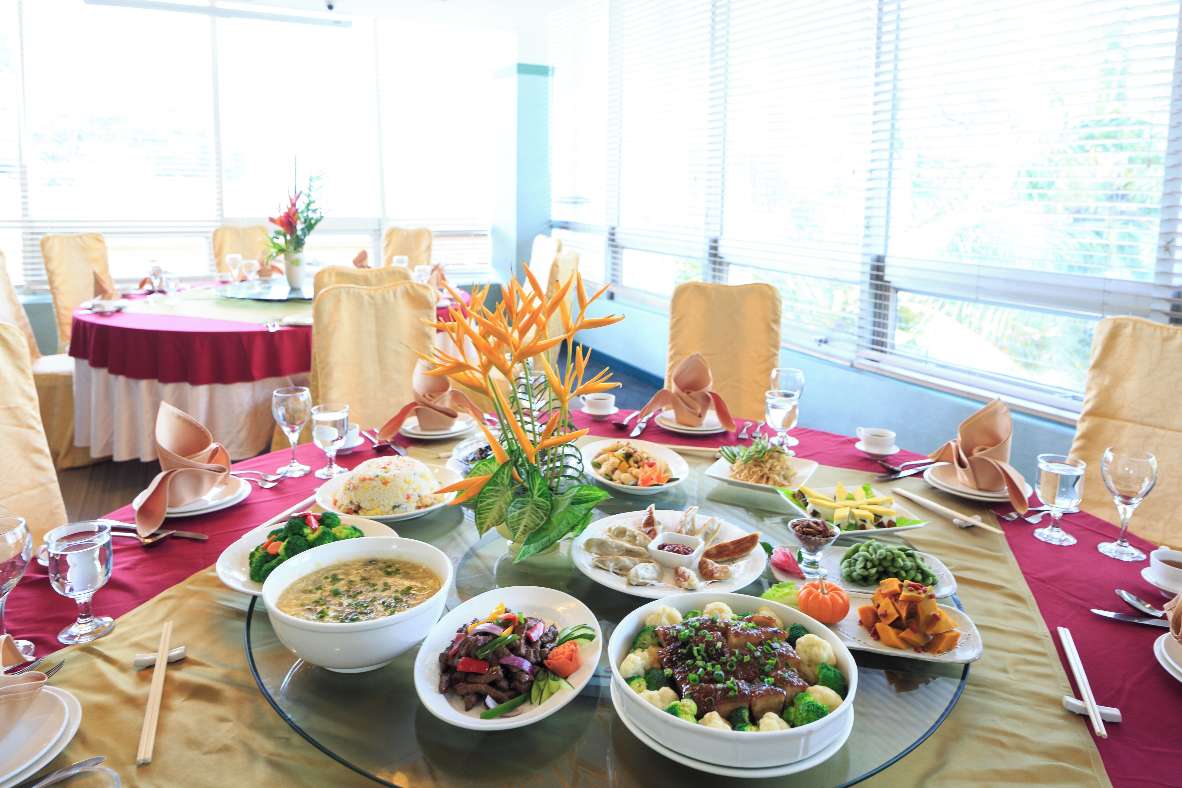 A dining table set for a meal with various dishes and a vase of flowers.