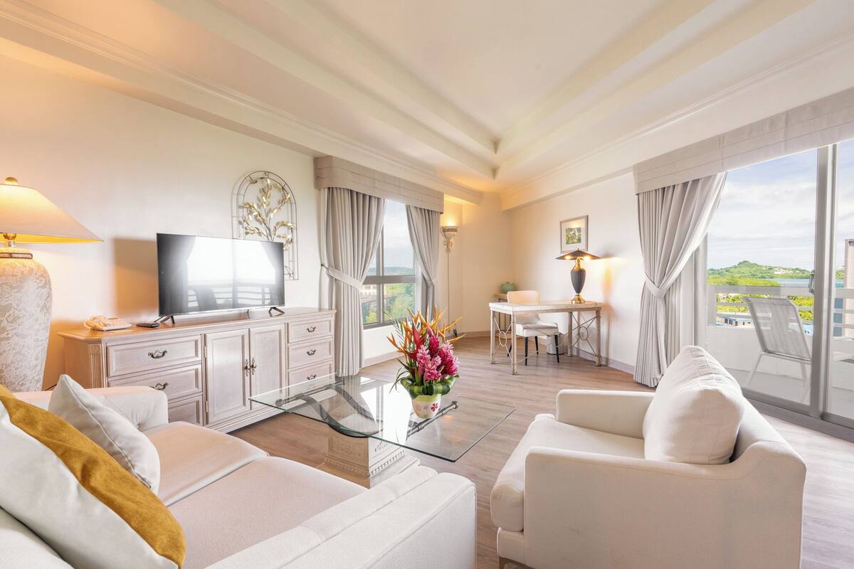 Een moderne hotelkamer met een zithoek, een eettafel en een balkon met uitzicht.