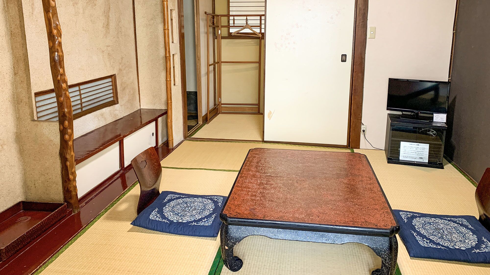 A traditional Japanese room with tatami flooring, a low table, and a television.