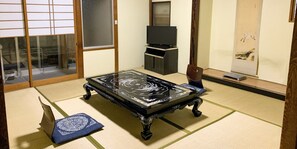 A tatami mat room with a low table, a television, and a traditional Japanese painting. - Beppu no OYADO Kagaya (Beppu)