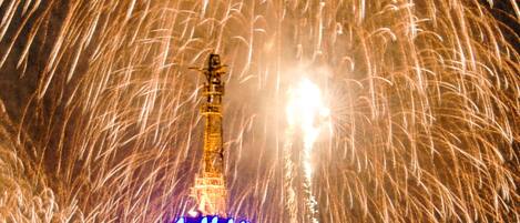 Una torre con un letrero iluminado en la base, rodeada de fuegos artificiales.