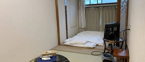 A small room with a bed, a desk with a computer, and a window with curtains.
