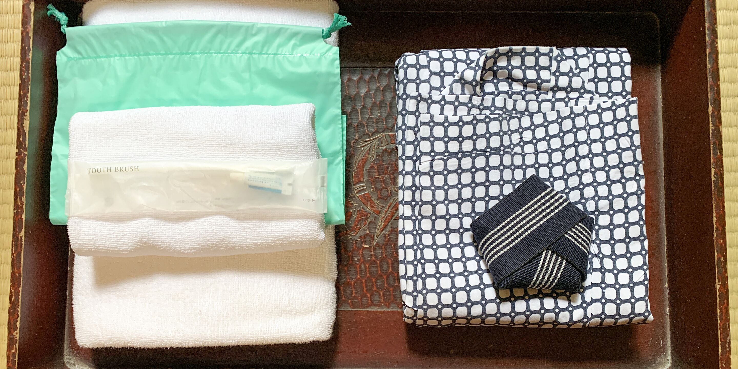 A bathroom with a green towel, a white towel, and a patterned towel with a striped item on it.