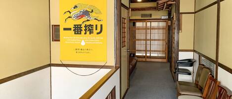 A traditional Japanese interior with tatami flooring, a sliding door, and a yellow sign with Japanese text.