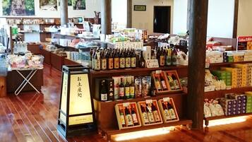 A spacious store with wooden floors and high ceilings, featuring shelves stocked with various products and a display area for items.