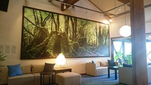A modern living room with a large forest-themed wall mural, a sofa, a coffee table, and a side table. - Yakushima Jomon No Yado Manten (Yakushima)