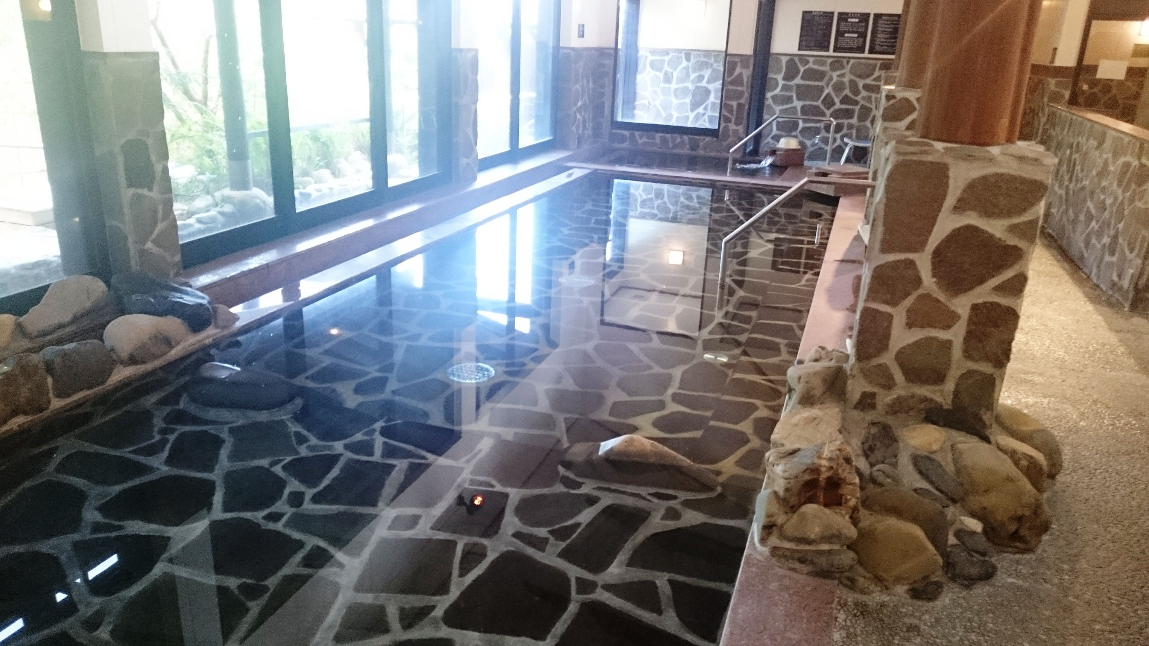 An indoor pool with a stone floor and a stone wall.