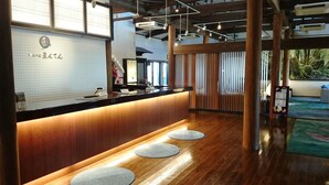 Un área de recepción con mostrador de madera, una mesa de recepción y vistas al exterior.